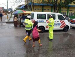 Ditengah Hujan dan Banjir, Kasat Lantas Polres Dumai Dorong Motor dan Seberangkan Pelajar Sekolah