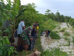 Babinsa Bersama Masyarakat Gotong Royong Buat Tanggul Penahan Air.